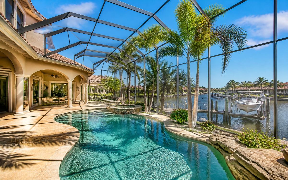 Screened Southwest Florida pool overlooking a Cape Coral canal with palm trees